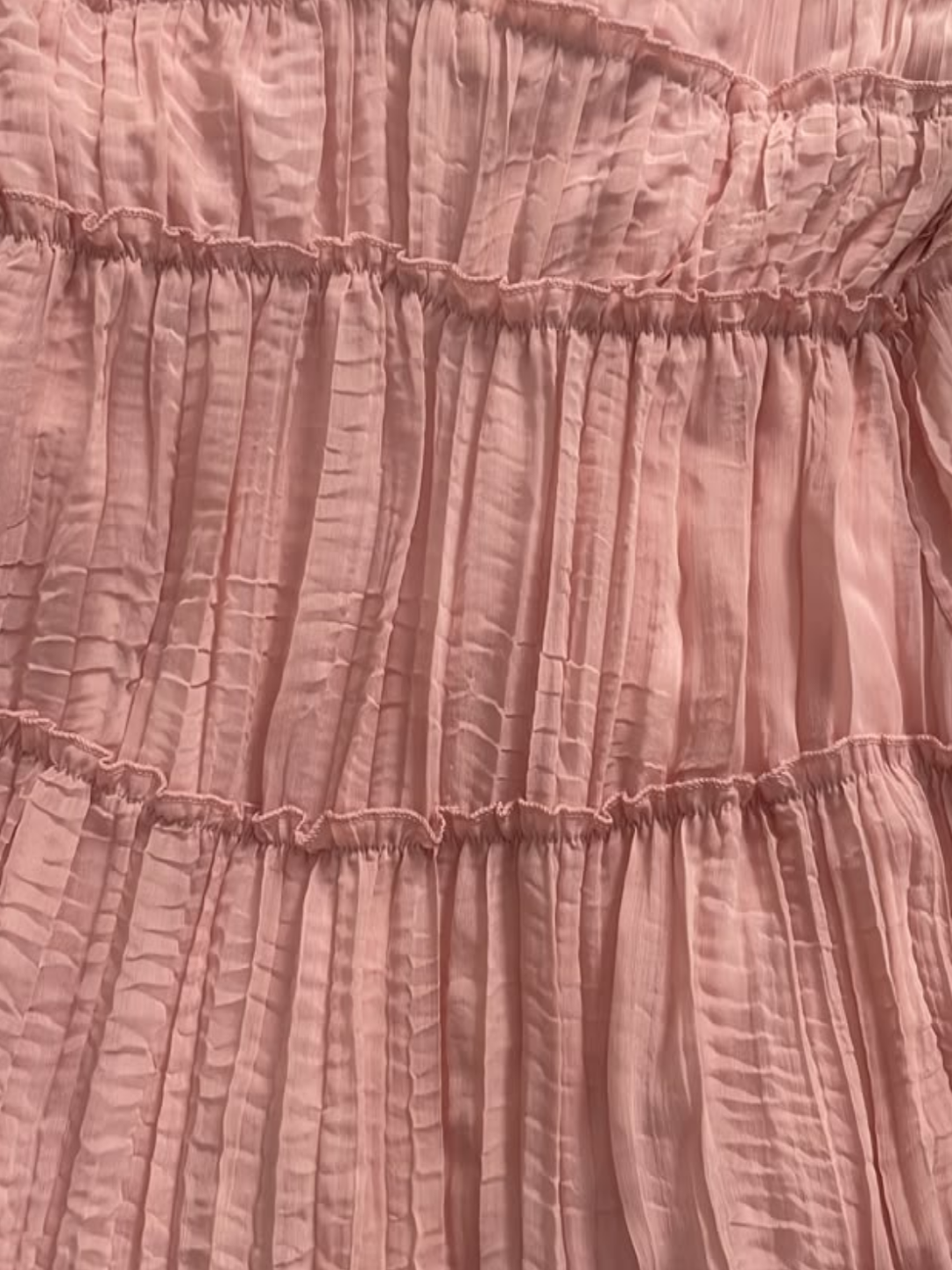 A close-up of a Villa Vibes Rya dusty pink crinkled fabric with horizontal gathered ruffles.