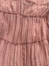 A close-up of a Villa Vibes Rya dusty pink crinkled fabric with horizontal gathered ruffles.