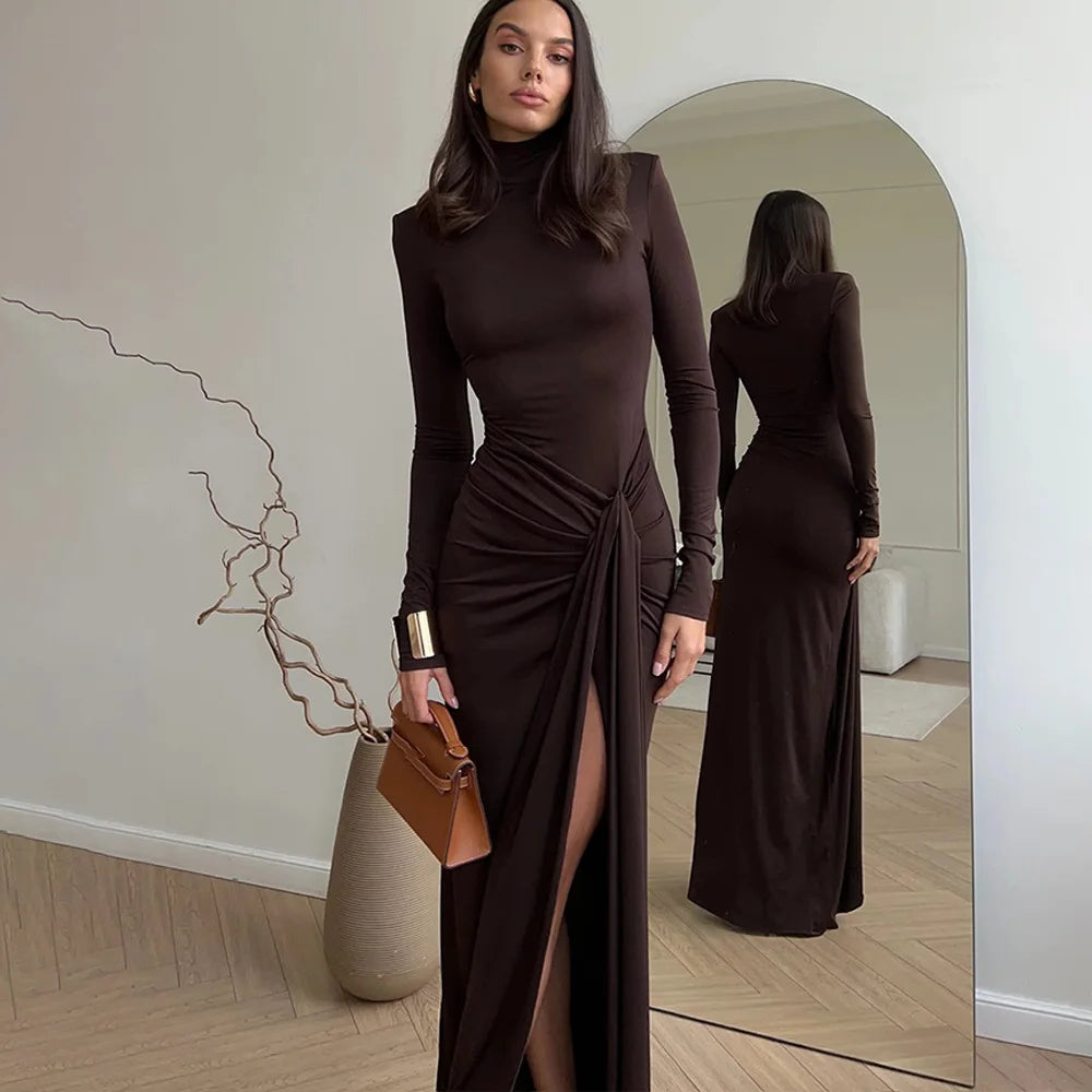 Woman in a Villa Vibes Allegra brown dress standing in front of a mirror, holding a brown handbag.