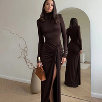 Woman in a Villa Vibes Allegra brown dress standing in front of a mirror, holding a brown handbag.