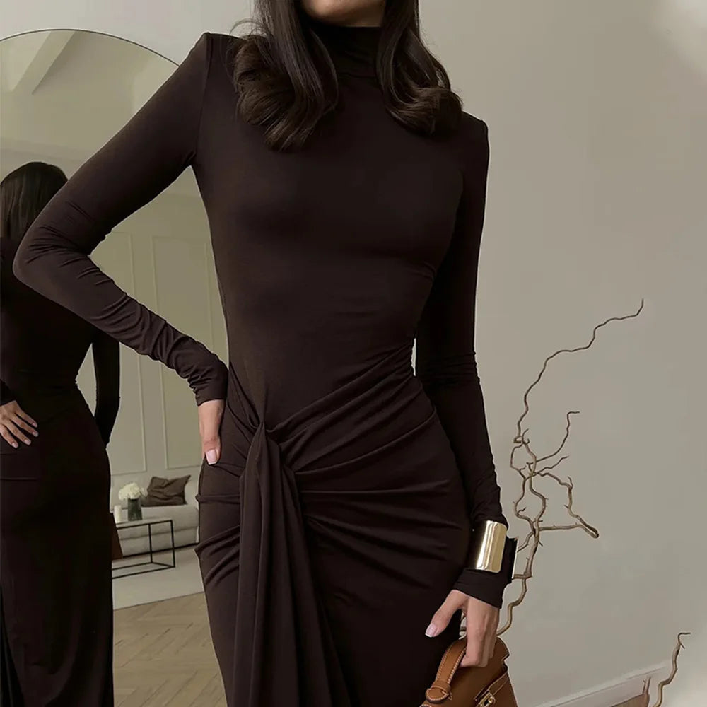 Woman wearing a Villa Vibes Allegra dark brown dress with a tie detail, standing in front of a mirror.