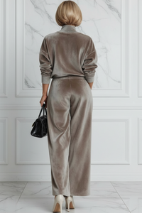 Person wearing a Villa Vibes Aster taupe velvet outfit with a black handbag against a marble wall.