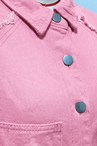 Close-up of a Villa Vibes Brydie pink denim jacket with buttons on a blue background