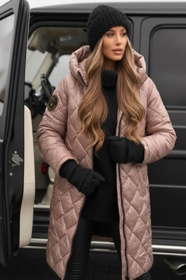 Woman in a VIlla VIbes Cameron long pink quilted coat standing next to a black vehicle.