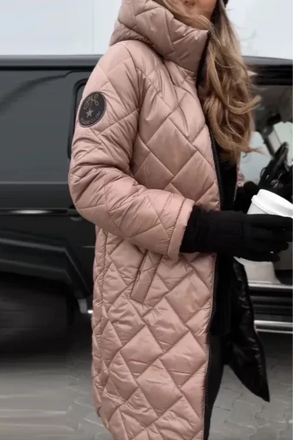 Person wearing a lVilla Vibes Cameron long quilted pink coat with a brand logo in front of a black vehicle.