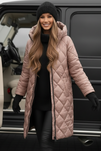 Woman in a Villa Vibes Cameron long pink quilted coat standing next to a black vehicle.