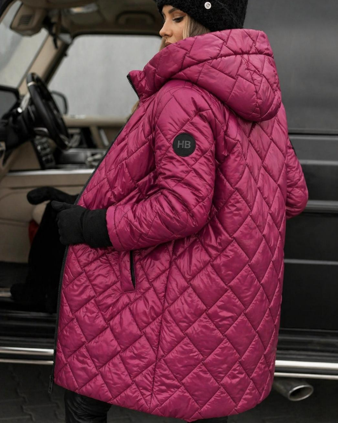 Person wearing a Villa Vibes Cameron Rose quilted coat with a brand logo, standing next to a vehicle.
