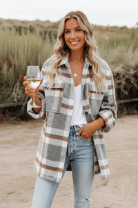 Woman in Villa Vibes Cassidy plaid shirt and jeans holding a glass outdoors