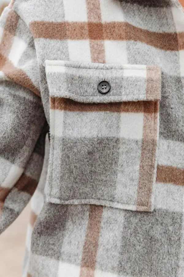 Close-up of a Villa Vibes Cassidy plaid shirt with a button on a neutral background