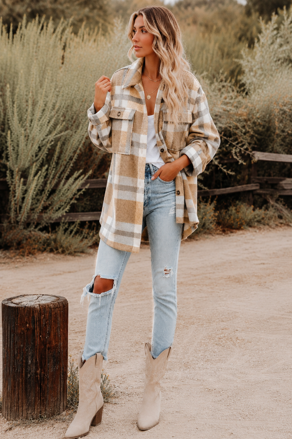 Woman wearing a Villa Vibes Cassidy plaid shirt, jeans, and boots in a natural setting