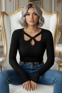 Woman sitting on an ornate chair wearing a Villa Vibes Dahlia black top and blue jeans.