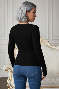 Woman wearing a Villa Vibes Dahlia black sweater and blue jeans in an elegant interior setting
