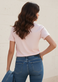 Woman wearing a Villa Vibes light pink t-shirt and blue jeans featuring the back of the tshirt