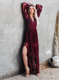 Woman in a Villa Vibes Janisburgundy lace dress standing against a textured wall.