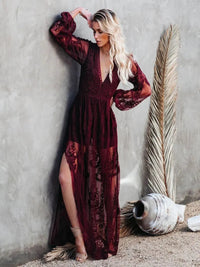 Woman in a Villa Vibes Janis burgundy lace dress standing against a textured wall with decorative elements.