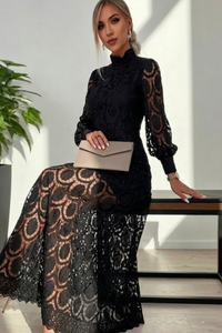 Woman wearing a Villa Vibes Jasmineblack lace outfit holding a beige clutch in an indoor setting.