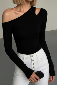 Person wearing a Villa Vibes Nikki black one-shoulder top and white pants with a blurred background