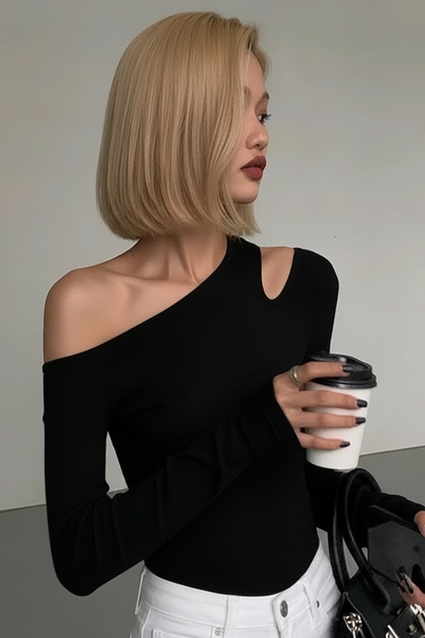 Woman in Villa Vibes Nikki black off-shoulder top holding a coffee cup against a neutral background