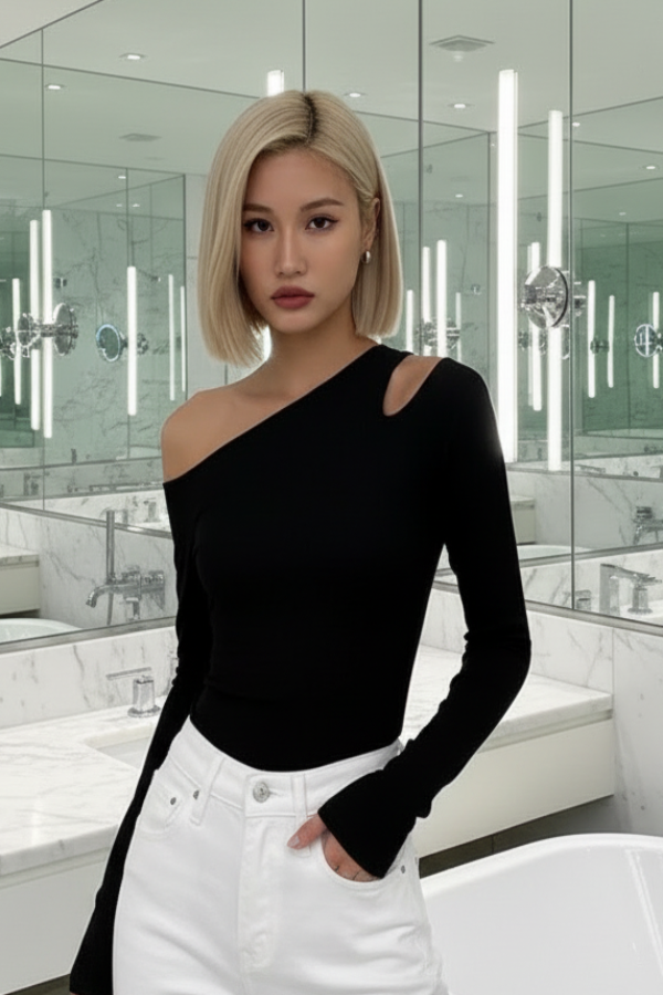 Woman wearing a VIlla Vibes Nikki black one-shoulder top and white pants in a bathroom setting