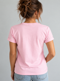 A woman viewed from behind wearing a Villa Vibes light pink short-sleeve crewneck t-shirt and light blue jeans, set against a solid light gray background.