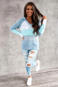Woman wearing a lVilla Vibes Pippa  blue and white striped sweater and ripped jeans against a gray concrete wall.