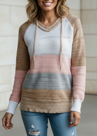 Woman wearing a Villa Vibes Pippa striped sweater and ripped jeans standing against a neutral background