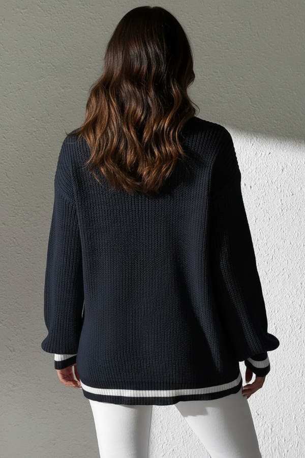 Person wearing Villa Vibes Sutton Navy sweater with white trim against a neutral wall.
