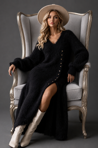Woman in a Villa Vibes black cardigan and white boots sitting on an ornate chair against a dark background