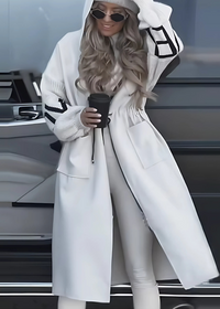 Person wearing Kelly long white coat with a car in the background
