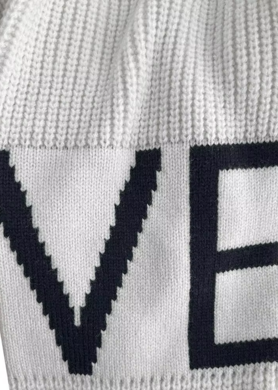 Close-up of White Kelly knit garment with 'LOVE' text in black on a white background