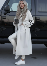 Woman in Kelly white outfit standing next to a black vehicle