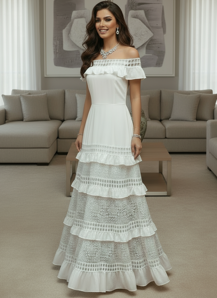 Woman in a white Alexa lace dress standing in a modern living room.