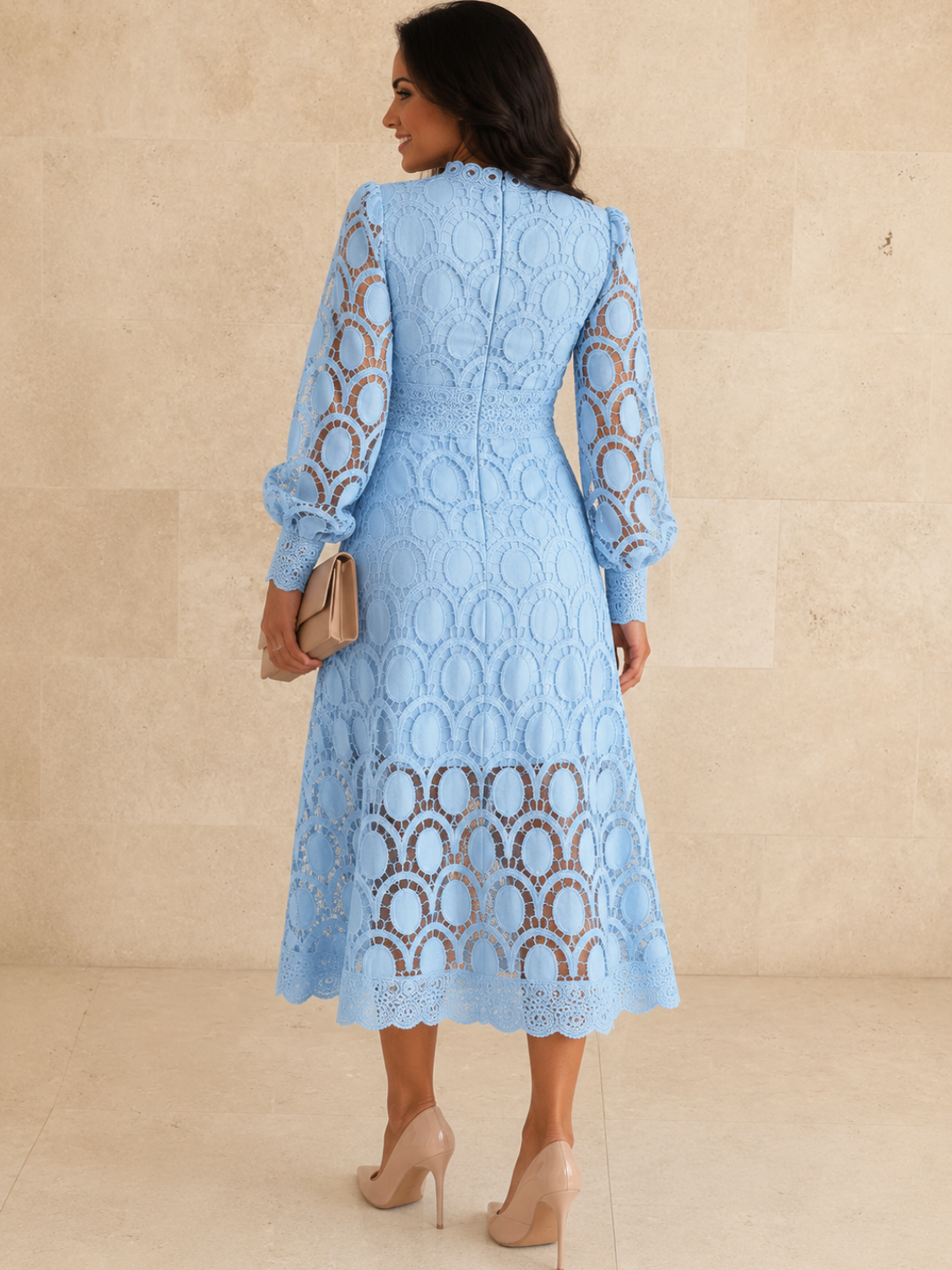 A woman shown from the back wearing a Villa Vibes Jasmine light blue lace midi dress with long sleeves and a fitted waist, standing against a beige stone wall and floor.