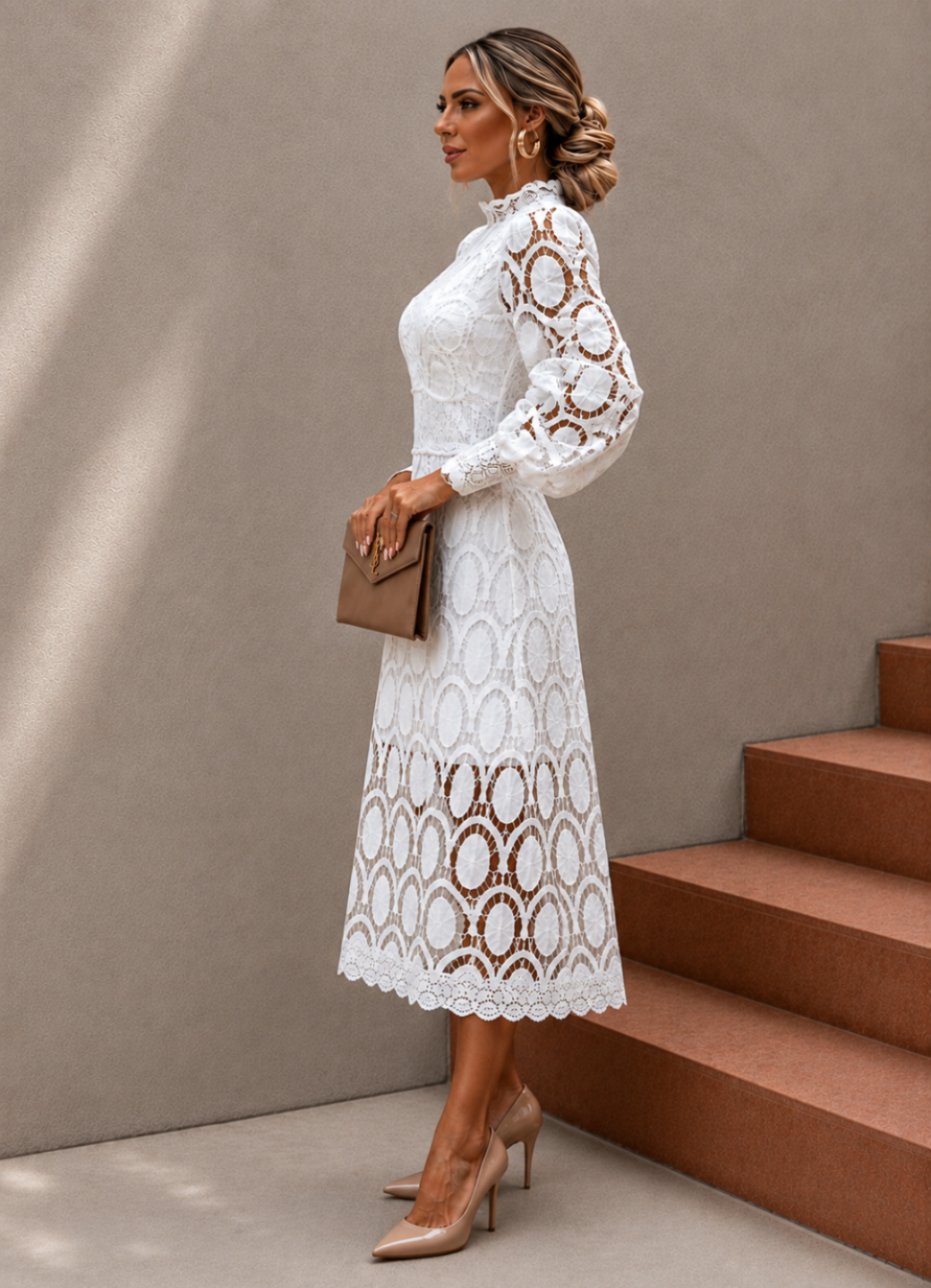 A woman models a Villa Vibes Jasmine white long-sleeve lace midi dress with a high ruffled collar, standing next to terracotta-colored steps against a textured beige wall.